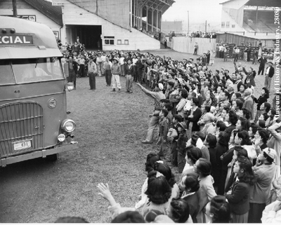 Group waving as bus departs, PI-28080